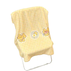 Gelbe Flanelldecke mit Karomuster und niedlichen Katzenmotiven, über einen Klappstuhl gelegt.