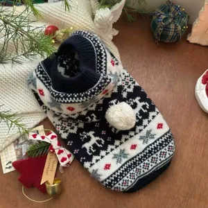 Detalle de un suéter tejido para mascotas con renos, copos de nieve, detalles rojos y pompón blanco