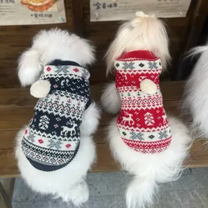 Dos perros blancos llevan jerséis de punto azul marino y rojo con motivos festivos y pompones