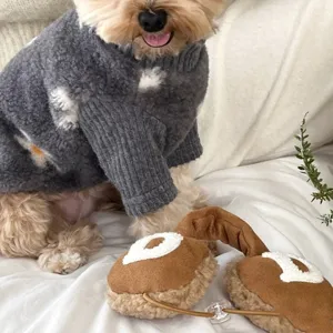 Small dog wearing a textured gray fleece sweater with white and cream spots, ribbed cuffs