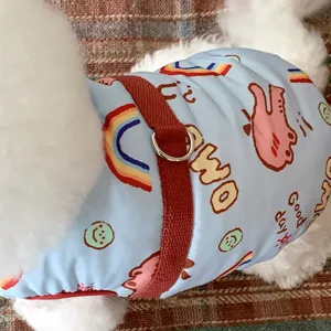 Gros plan sur motifs arc-en-ciel et smiley, sangle rouge et anneau métallique sur tissu bleu.