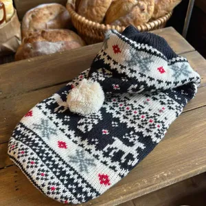 Detalle del tejido blanco y negro con renos, copos de nieve, toques rojos y pompón blanco