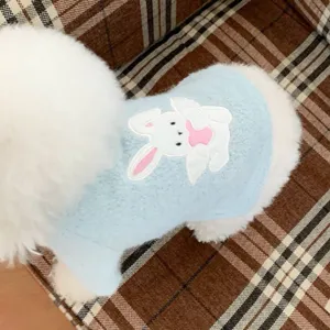Close-up of a pale blue plush dog vest with white rabbit appliqué and soft white trim