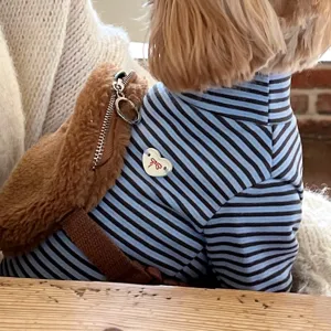 Close-up of a blue and brown striped knit pet top, heart-shaped charm and plush pouch