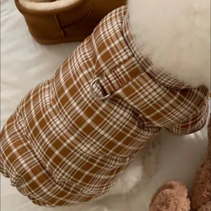 Gros plan sur le matelassage à carreaux brun et crème, le col blanc en peluche et l'anneau métallique.