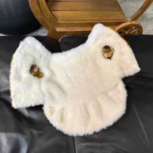 Prenda blanca de peluche con ventilación redonda, ribete marrón y bajo con volantes, extendida