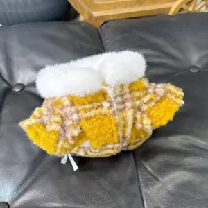 Primer plano de un abrigo de cuadros amarillo y crema, con cuello blanco mullido y botones
