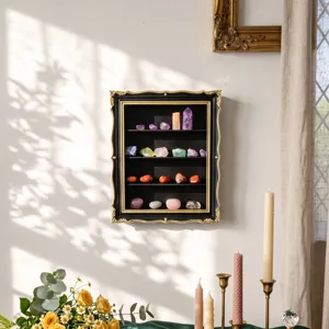 Wall-mounted black display cabinet with ornate gold trim, four shelves, and colorful crystals