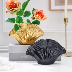 Vases dorés et noirs en éventail, aux reliefs rayonnants, présentés avec des roses sur une table