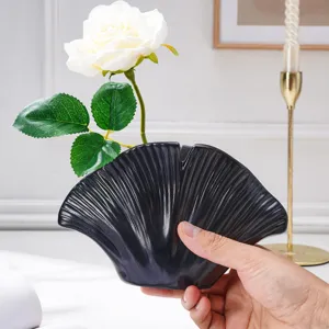 Vase noir en céramique en éventail, à rainures rayonnantes, avec une rose blanche en gros plan
