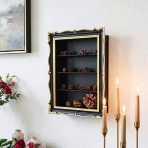 Wall-mounted black display cabinet with ornate gold trim, glass front, shelves and natural finds