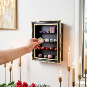 Hand placing colorful crystals on the tiered shelves of an ornate wall display case