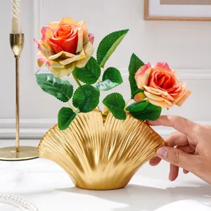 Vase doré en forme d’éventail, à reliefs rayonnants, avec des roses orange et des feuilles vertes