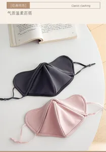 Two sculpted fabric masks in charcoal gray and pink, with adjustable ear loops on a white table