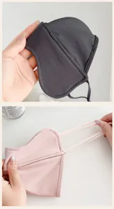 Close-up detail of gray and pink contoured fabric masks with ear loops, held by hand