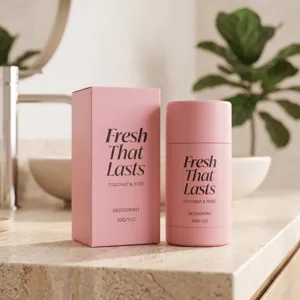 Stick déodorant rose et boîte assortie sur un comptoir de salle de bains, près d’une plante verte
