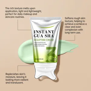 Skincare cream tube with a gua sha-shaped cap, shown over a green cream smear on a beige background.