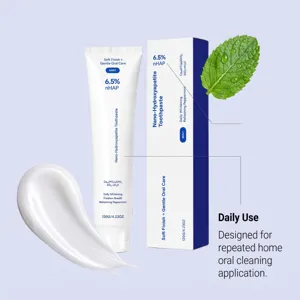 Toothpaste tube and box with a mint leaf and a white paste smear on a pale lavender background
