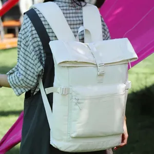 Zaino minimalista color avorio con patta, tasca frontale con zip e fibbie, indossato all'aperto