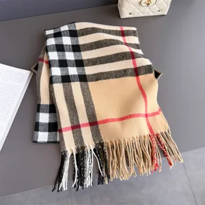 Écharpe beige à carreaux noirs, blancs et rouges, avec longues franges, posée sur table grise