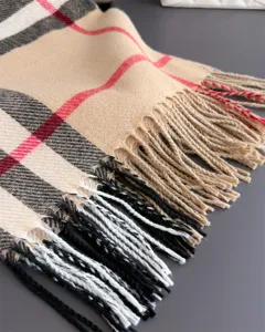Gros plan sur un tissu à carreaux tissé, beige avec des rayures rouges et noires et des franges