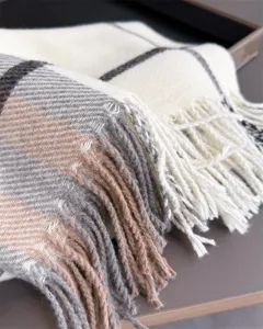 Gros plan sur le tissu à carreaux doux, crème, gris et camel, avec des franges finies à la main