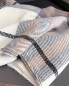 Gros plan sur un tissu à carreaux crème, gris, taupe et brun foncé, au toucher doux et bord frangé