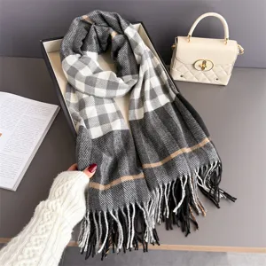 Détail du tissu à carreaux gris, avec des rayures beiges et de longues franges dans un coffret cadeau