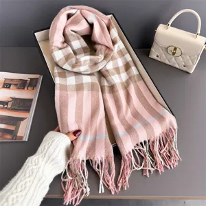 Écharpe à carreaux roses à franges présentée dans une boîte cadeau près d’un sac à main beige