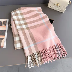 Écharpe à carreaux rose et beige, à franges, présentée à plat sur une surface grise