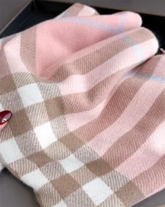 Gros plan sur le tissu doux à carreaux rose, beige et blanc, avec de fines lignes bleues et des plis