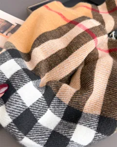 Gros plan sur une écharpe à carreaux plissée, camel, noire, blanche et rouge, au tissage diagonal
