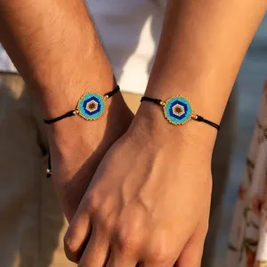 Primer plano de dos muñecas con adornos de ojo azul hechos de cuentas y cordones negros ajustables