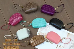 Overhead view of eight croc-textured pouches in assorted colors, with zippers and wrist straps