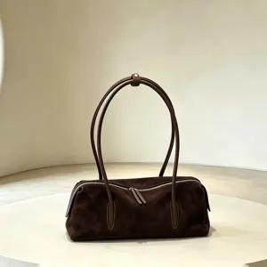 Dark brown suede bag with twin rounded handles and a silver zipper, displayed on a beige pedestal