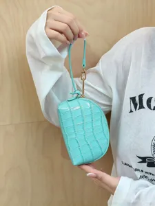 Close-up of a turquoise crocodile-embossed wristlet pouch with gold clasp, held by hand