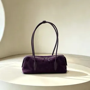 Purple suede-textured bag with long handles and top zipper, displayed on a pale round table