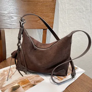 Brown suede bag with a curved silhouette, shoulder strap, zipper and metal hardware
