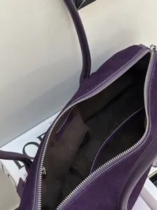 Close-up view of the dark lining inside an open purple suede bag, with silver zipper teeth