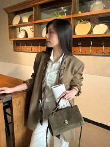 Olive khaki suede-textured handbag with metal turn-lock, styled with a blazer in a café