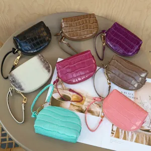 Overhead view of colorful small crocodile-embossed leather wristlet pouches with gold-tone zippers