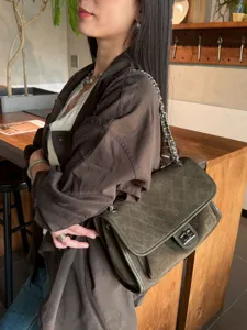 Vista lateral de una modelo con bolso acolchado verde oliva, cadena plateada y cierre metálico