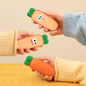 Drei orangefarbene USB-Handwärmer in Karottenform mit grünen Blättern, zwei mit lustigen Gesichtern