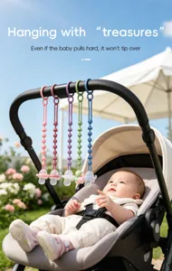 Five colorful beaded pacifier clips hang from a stroller handle beside a baby outdoors