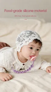 Baby wearing a purple silicone pacifier clip with pink pacifier, shown in a soft nursery scene