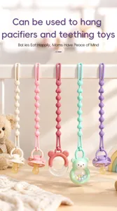 Five beaded silicone pacifier straps in ivory, pink, red, mint and purple hang on a crib rail