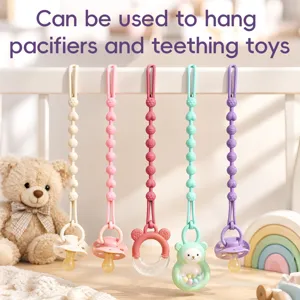 Five-color silicone pacifier clip chains with pacifiers and a teether hanging on a crib rail