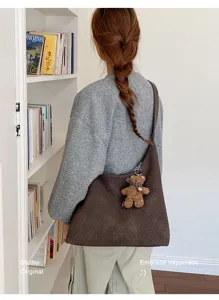 Vue de dos d’une personne portant un sac brun tressé avec un petit porte-clés en forme d’ourson