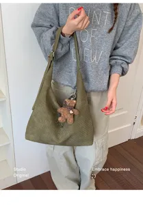 Sac cabas olive à texture tressée, porté à l’épaule avec une sangle réglable et un petit ours brun