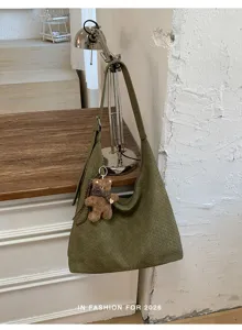 Sac tissé vert olive suspendu à une lampe, avec un ourson brun et une écharpe à carreaux